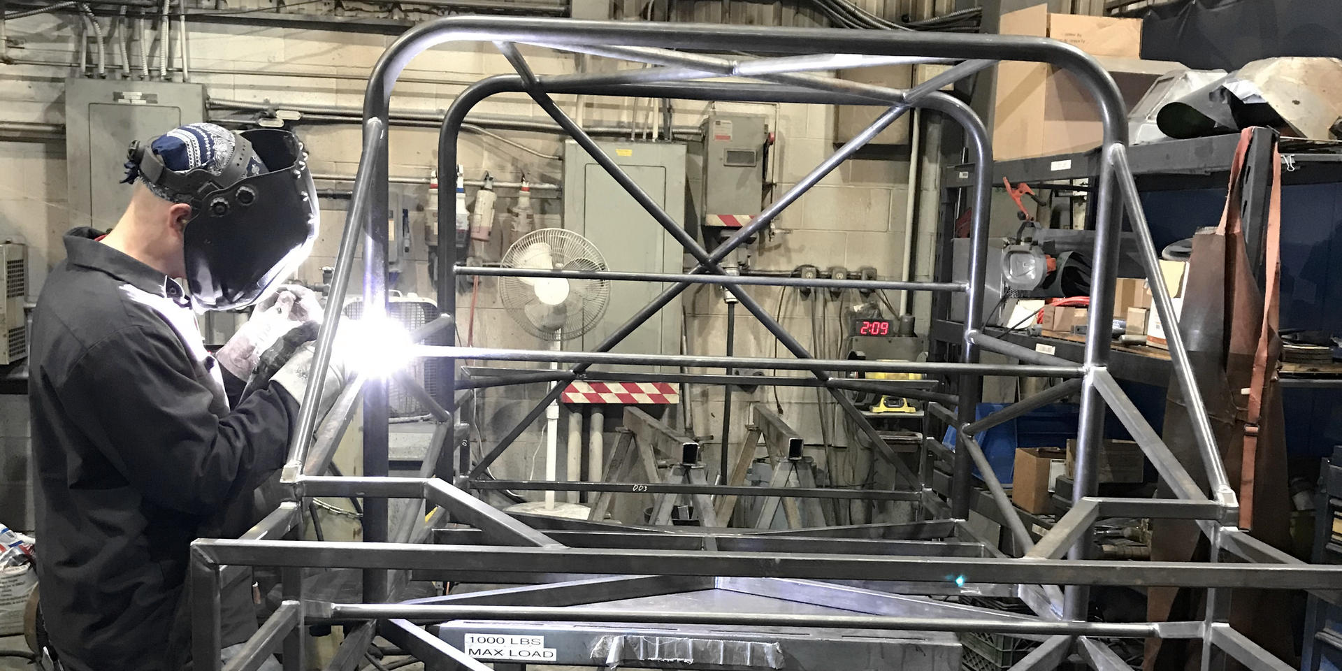 Welder assembling an automobile frame for Western University's Engineering program.